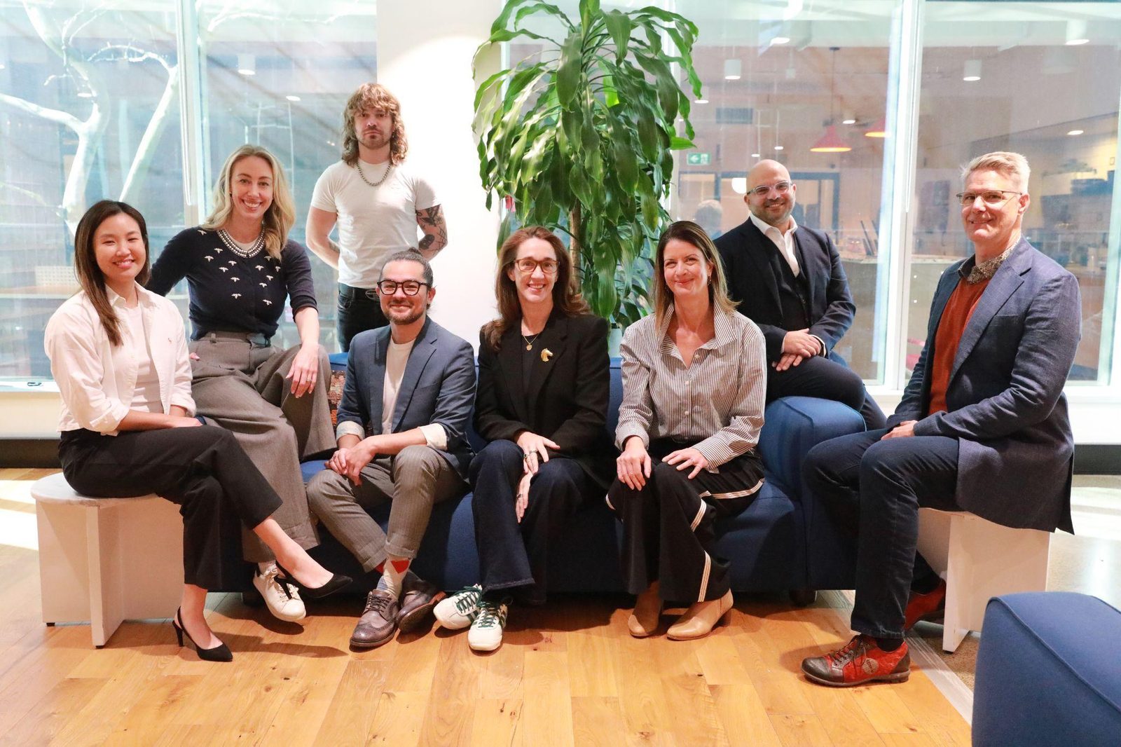 Nine members of the Bella Sl&aacute;inte team seated together in a bright office, smiling towards the camera